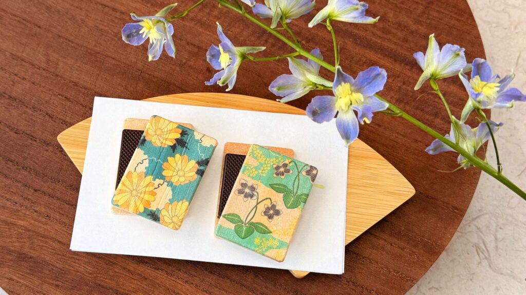 叶匠壽庵_ダークチョコレートが挟まれた「心よせ結」と花が並んでいる様子