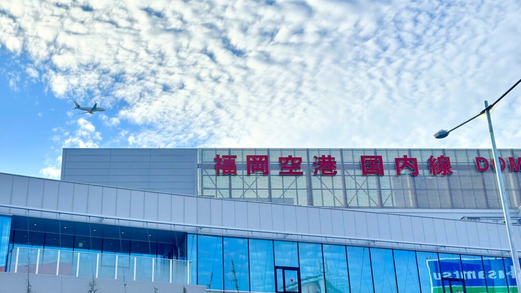 福岡空港_正面玄関にある看板と飛行機が飛んでいる様子