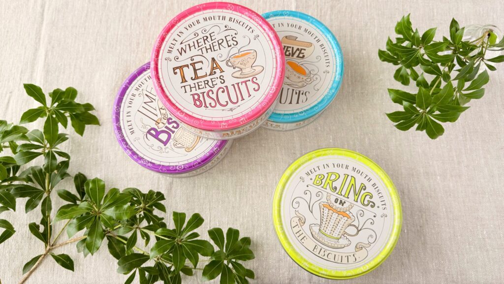 ヤコブセン_4色の「ティータイムバタークッキーティン150g」のパッケージと葉っぱが飾られている様子