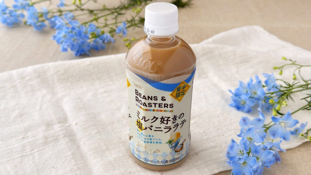 UCC_「UCC BEANS ROASTERS ミルク好きの塩バニララテ PET450ml」のパッケージと花が添えられている様子