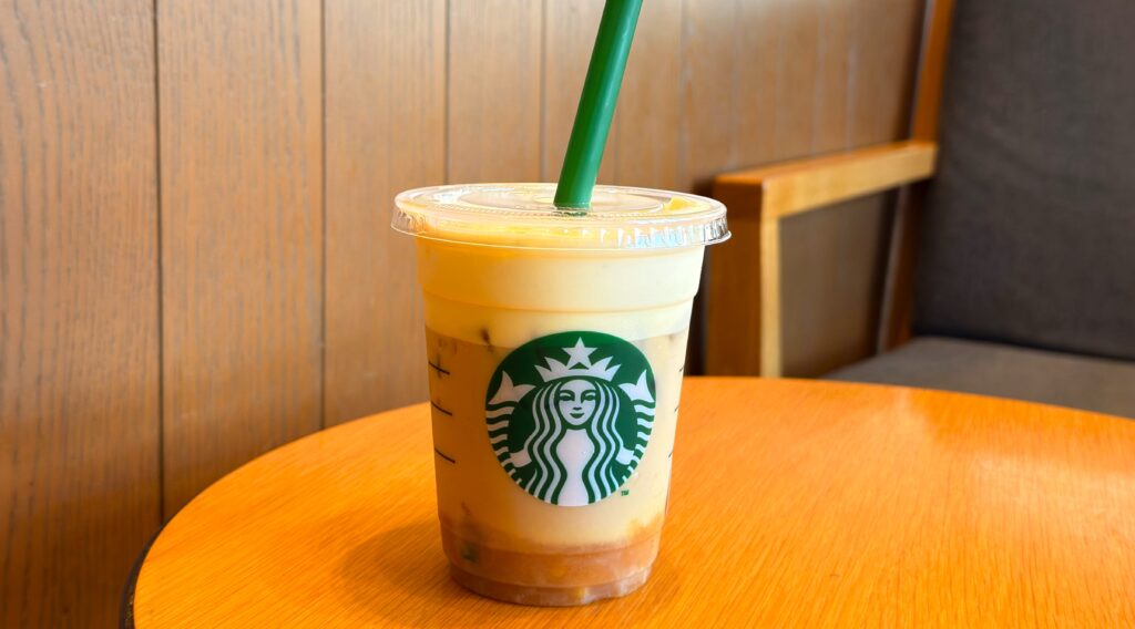 スターバックス_「ほうじ茶香る 焼き芋 ムース ティー ラテ」にストローをさしている様子