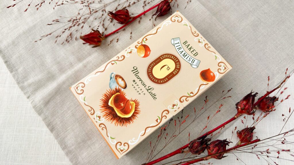 シーキューブ_「焼きティラミス マロンラテ」の4個入パッケージとお花が並んでいる様子