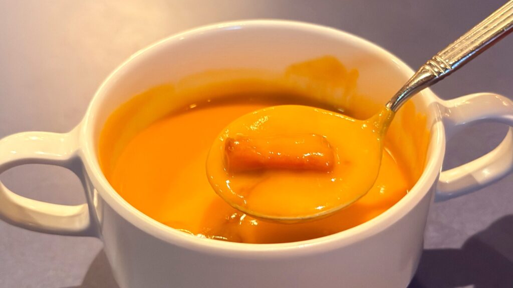 ディズニーシー_ホライズンベイ・レストラン「スペシャルセット」のパンプキンクリームスープをスプーンですくっている様子