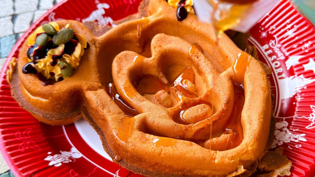 ディズニーランド_「ミッキーワッフル、パンプキンホイップとメイプルソース」にソースをかけている様子