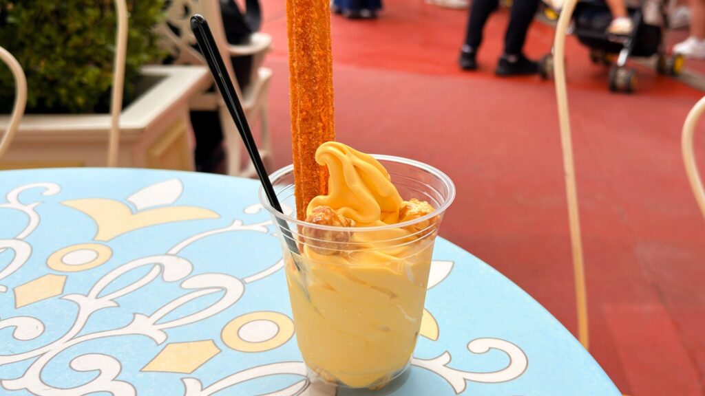 東京ディズニーランド・シー_ハロウィーン限定「ハロウィーンサンデー（パンプキンソフトクリーム＆チュロス）」がテーブルの上に置いてある様子
