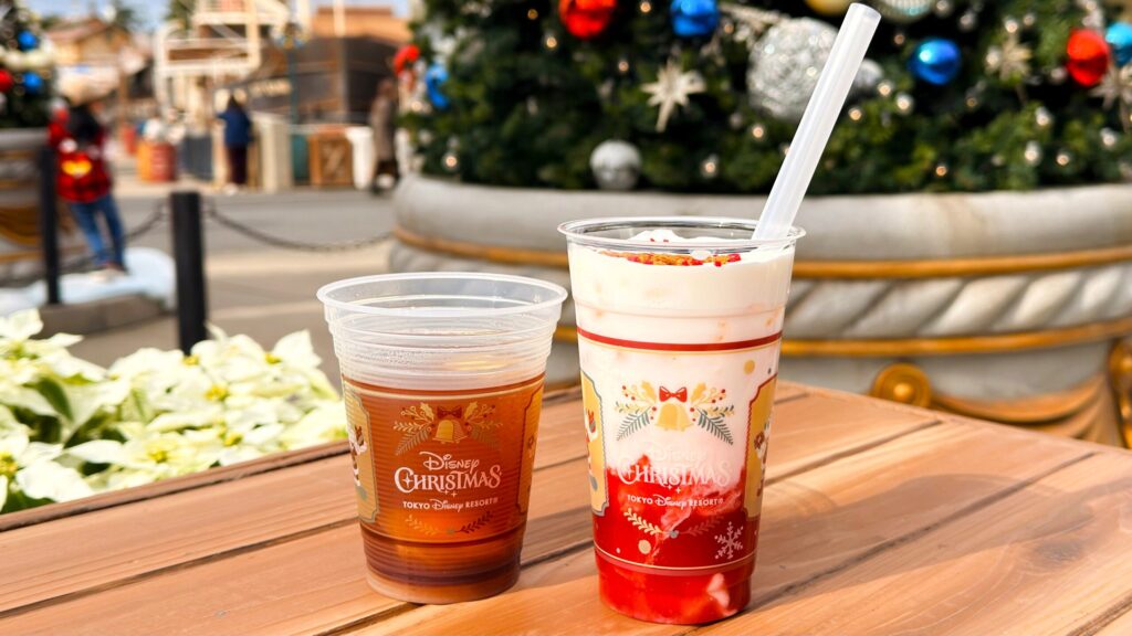 ディズニーリゾート_期間限定ドリンク「ホットアップルジンジャードリンク」と「スペシャルドリンク（苺ミルク）」がツリーの前に並んでいる様子