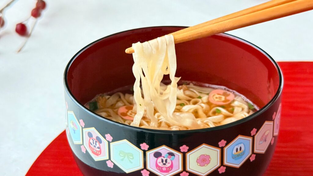 東京ディズニーリゾート_「ミニうどん 紙箱 ミッキーマウスと仲間たち」の麺を箸で持っている様子
