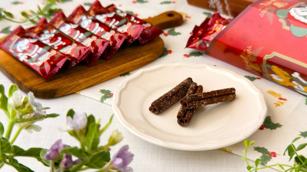 東京ディズニーリゾート_チョコレート風味「チュロススナック 紙箱 ミッキーマウスと仲間たち ディズニー・クリスマス」の皿盛りとパッケージが並んでいる様子