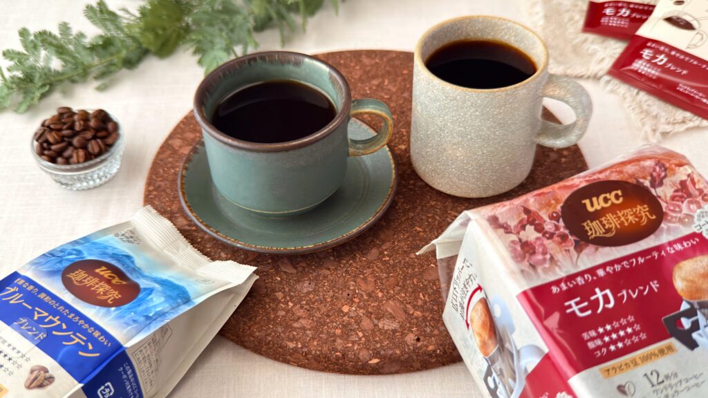 UCC_マグカップに注いだ「UCC 珈琲探究 炒り豆 ブルーマウンテンブレンド」と「UCC 珈琲探究 ワンドリップコーヒー モカブレンド」がテーブルの上に置いてある様子