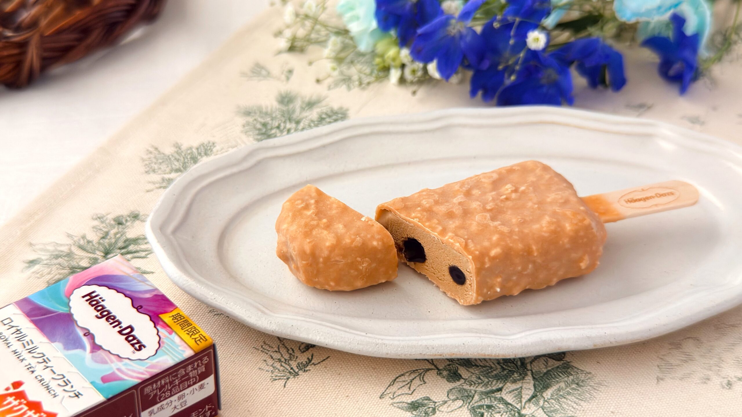 ハーゲンダッツ_ミルクティーチョコレートコーティングされた「ロイヤルミルクティークランチ」とお花が置いてある様子