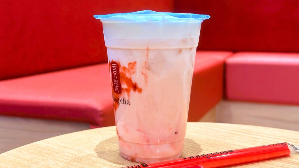 ゴンチャ_いちご杏仁トッピングがはいった「いちご杏仁 ミルクティー 」がテーブルの上に置いてある様子