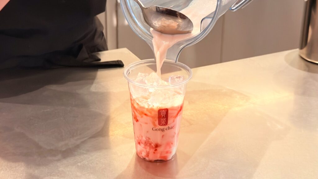 ゴンチャ_「いちご杏仁 ミルクティー 」の阿里山ウーロンミルクティーをカップに注いでいる様子