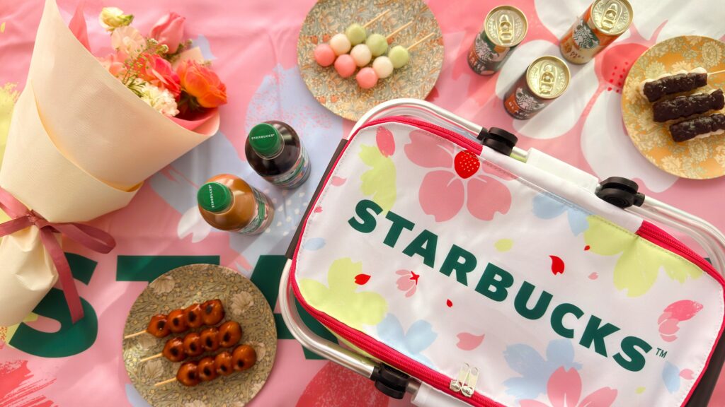 スターバックス_SAKURAキャンペーン「スターバックスオリジナルレジャーシート」の上に「スターバックスオリジナル保冷バッグ」や団子などが並んでいる様子