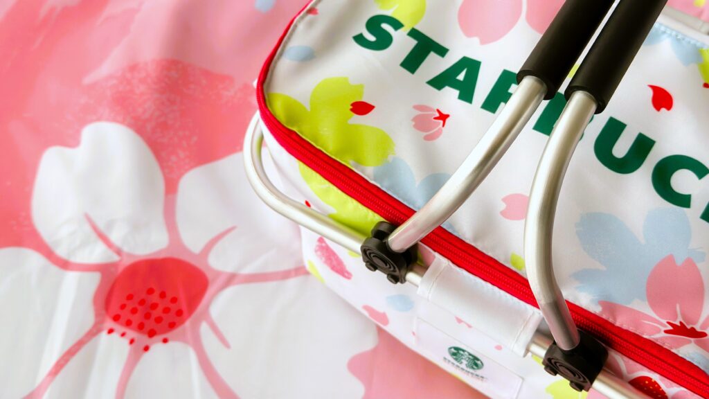 スターバックス_SAKURAキャンペーン「スターバックスオリジナルレジャーシート」の上に「スターバックスコーヒーオリジナル保冷バッグ」とが置いてある様子