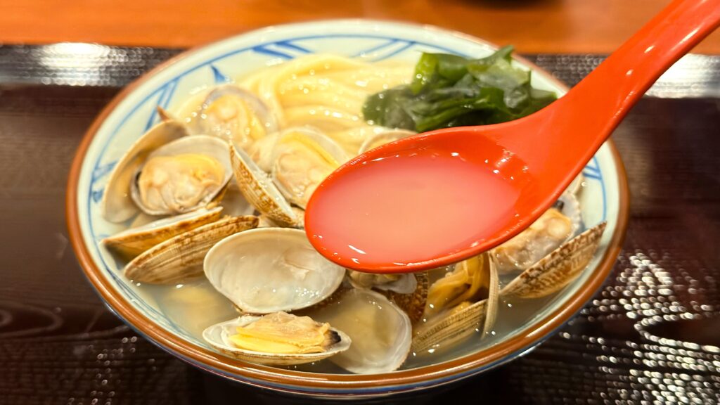 丸亀製麺_「山盛りあさりうどん」のスープをレンゲですくっている様子
