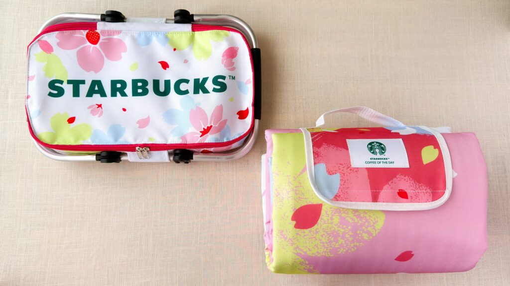 スターバックス_SAKURAキャンペーンの「スターバックスコーヒーオリジナル保冷バッグ」と「スターバックスオリジナルレジャーシート」がたたんだ状態で置いてある様子