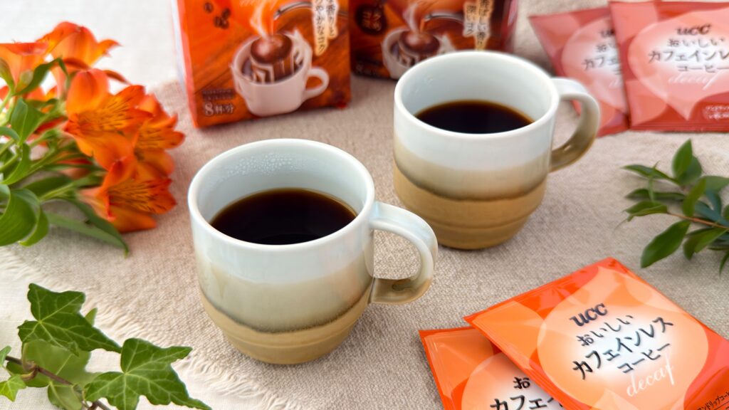 UCC_淹れたての「おいしいカフェインレスコーヒーワンドリップコーヒー」と「おいしいカフェインレスコーヒーワンドリップコーヒー コク深め」とパッケージが並んでいる様子