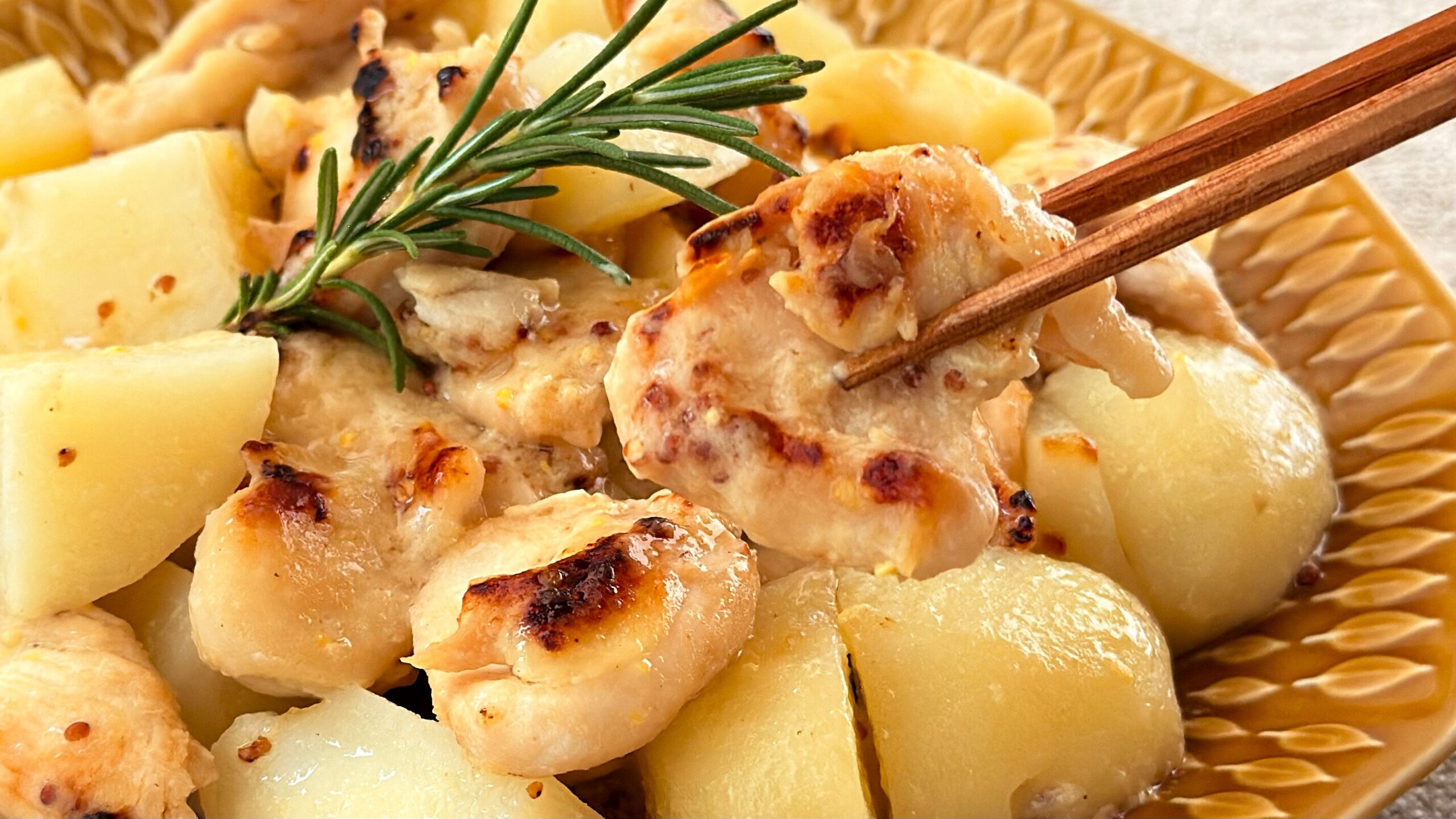 大塚食品_「メインディップ 鶏ももポテトのハニーマスタード」の鶏もも肉を箸で持っている様子