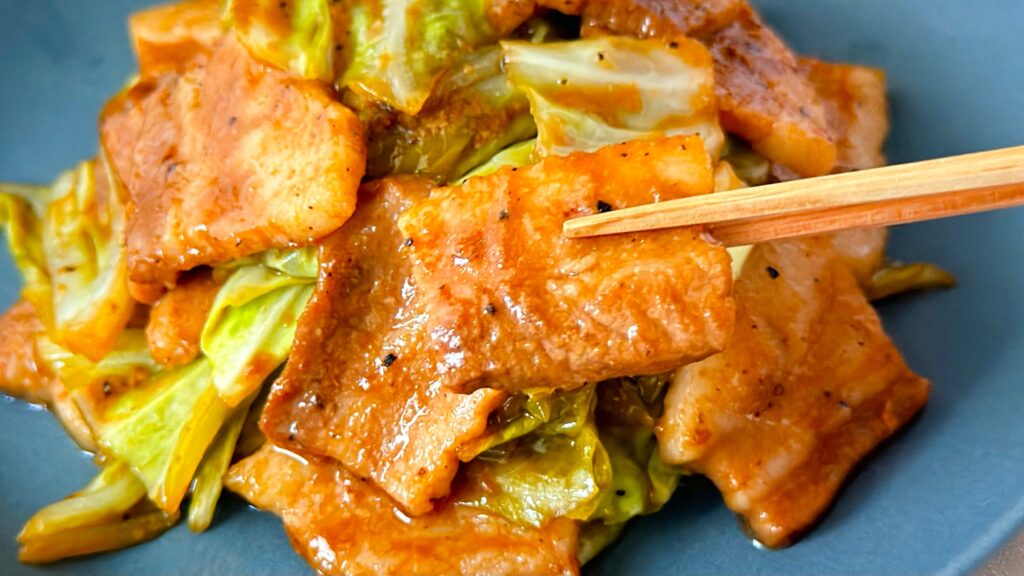 大塚食品_「メインディップ 豚バラキャベツのローストガーリック炒め」の豚バラ肉を箸で持っている様子