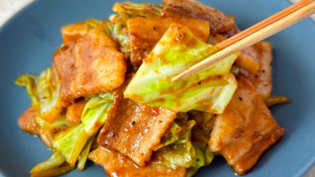 大塚食品_「メインディップ 豚バラキャベツのローストガーリック炒め」のキャベツを箸で持っている様子