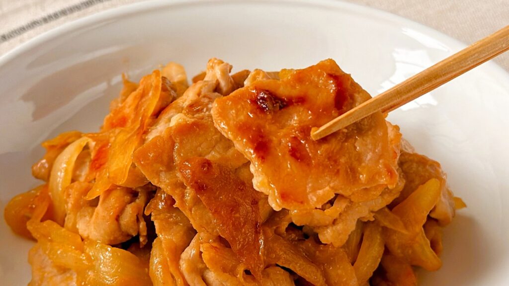 大塚食品_「メインディップ 豚ロース玉ねぎのしょうが焼き」の豚ロースを箸で持っている様子