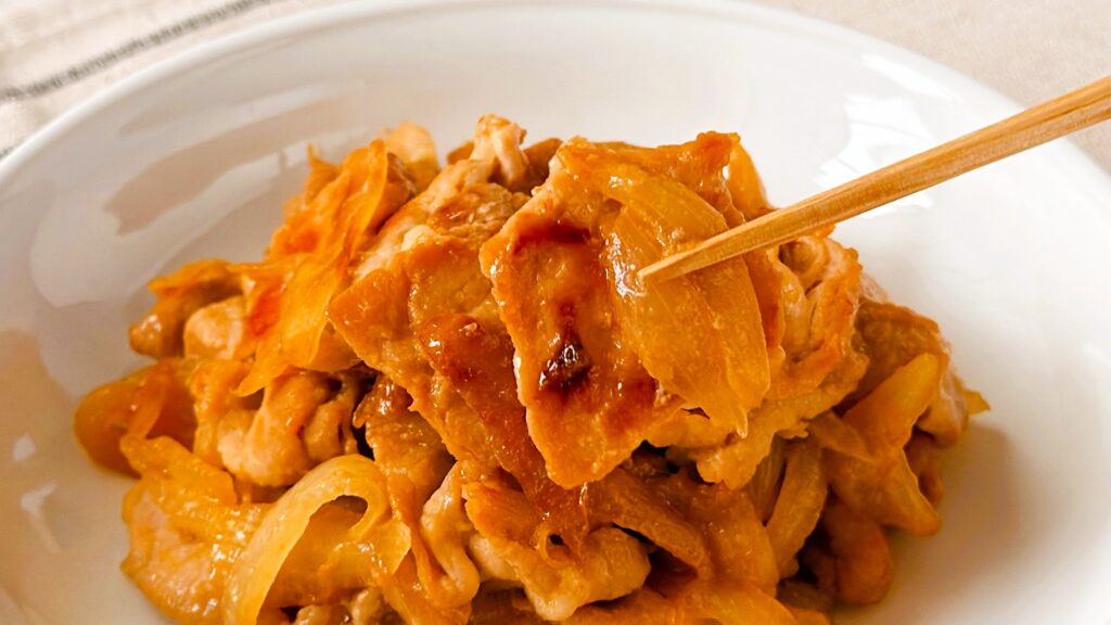 大塚食品_「メインディップ 豚ロース玉ねぎのしょうが焼き」の豚ロースと玉ねぎを箸で持っている様子