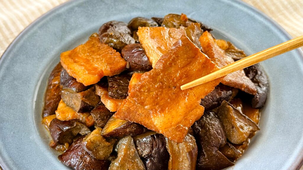 大塚食品_「メインディップ 豚バラなすのバルサミコ炒め」の豚バラを箸で持っている様子