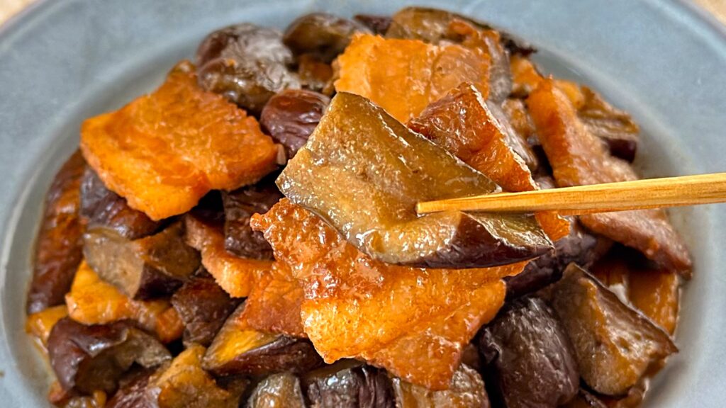 大塚食品_「メインディップ 豚バラなすのバルサミコ炒め」のなすを箸で持っている様子