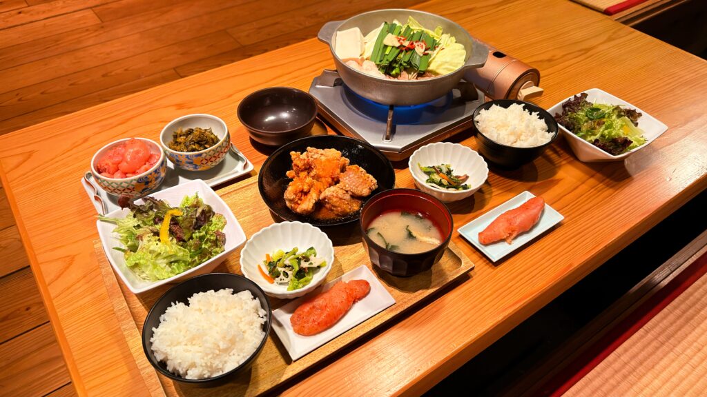 やまや_「熟成鶏の唐揚げめんたい風味定食」と「やまや自慢のもつ鍋膳」がテーブルの上に並んでいる様子