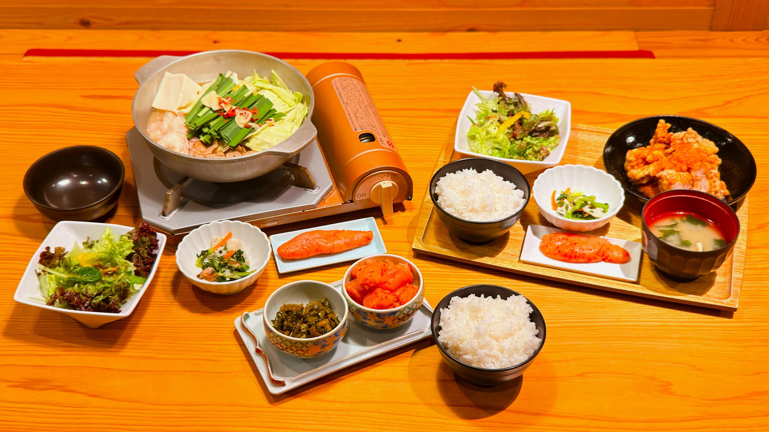 やまや_テーブルに並んだ「熟成鶏の唐揚げめんたい風味定食」と「やまや自慢のもつ鍋膳」