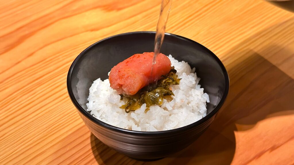 やまや_明太子とからし高菜がのったご飯にうまだしをかけている様子