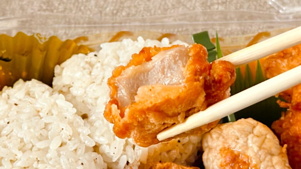 やまや_「やまや うまだしおにぎりセット」のから揚げを箸で持っている様子
