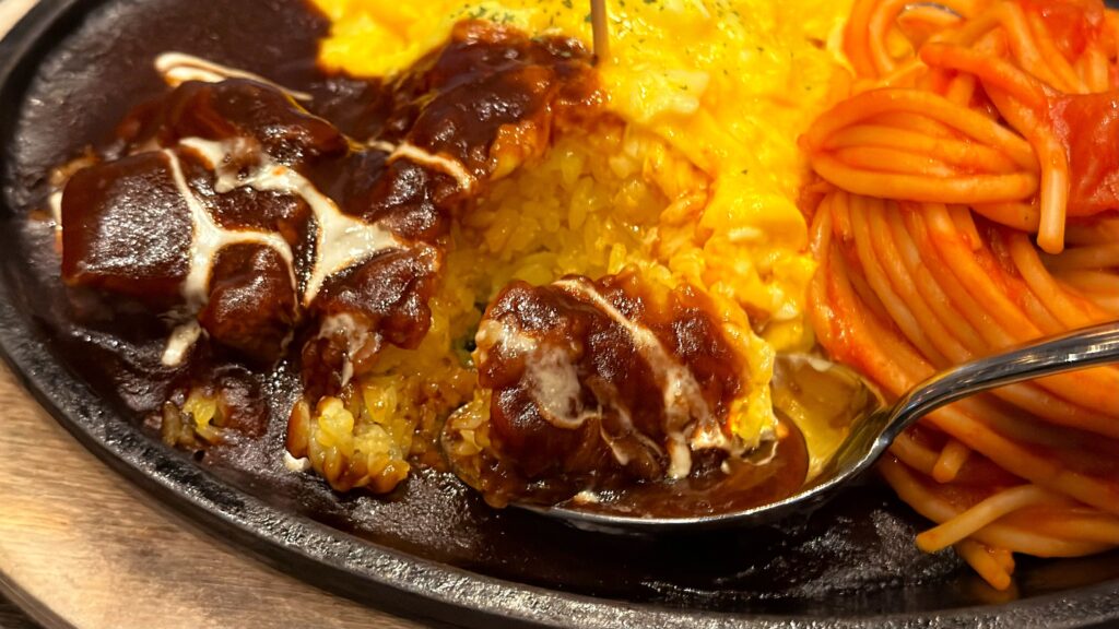 ホテルニューアカオ_メインダイニング錦の「ハーフビュッフェランチ」の選べるメインディッシュ「ナポリタン×オムライスプレート」のオムライスをスプーンですくっている様子