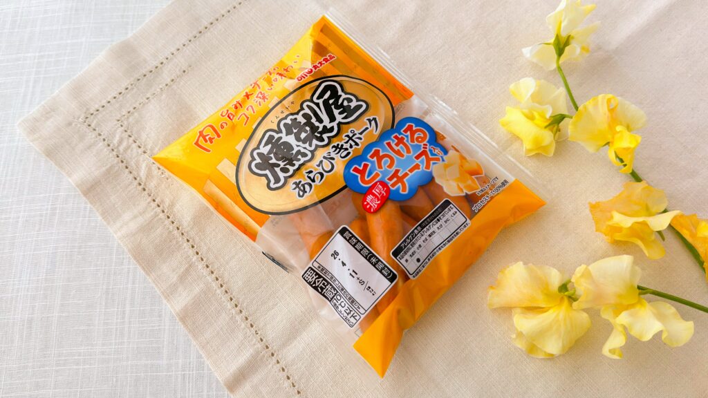 丸大食品_「燻製屋熟成ウインナー とろける濃厚チーズ」とお花が並んでいる様子