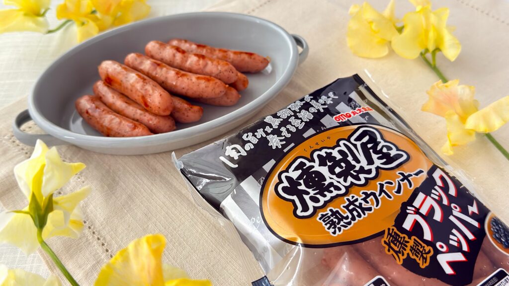 丸大食品_焼いた「燻製屋熟成ウインナー ブラックペッパー」の皿盛りとパッケージ