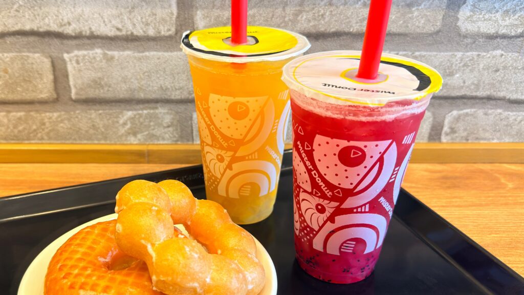 ミスタードーナツ_ストローをさした「ぷにゅんフングイフルーツティ ピーチ&ドラゴンフルーツ」と「ぷにゅんフングイフルーツティ パイン&マンゴー&パッションフルーツ」、ドーナツ皿もり