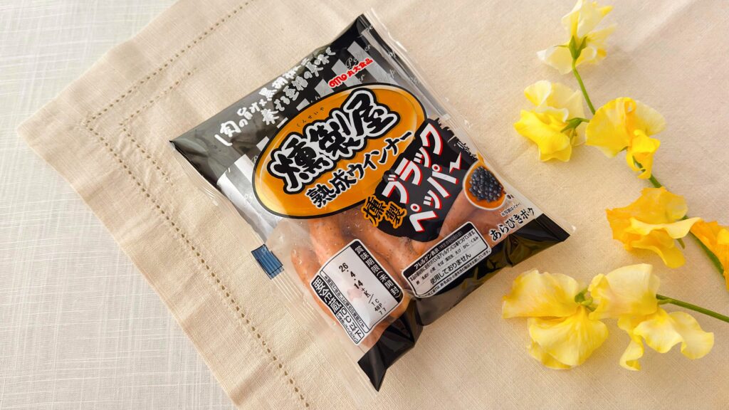 丸大食品_斜めに置いた「燻製屋熟成ウインナー ブラックペッパー」のパッケージ
