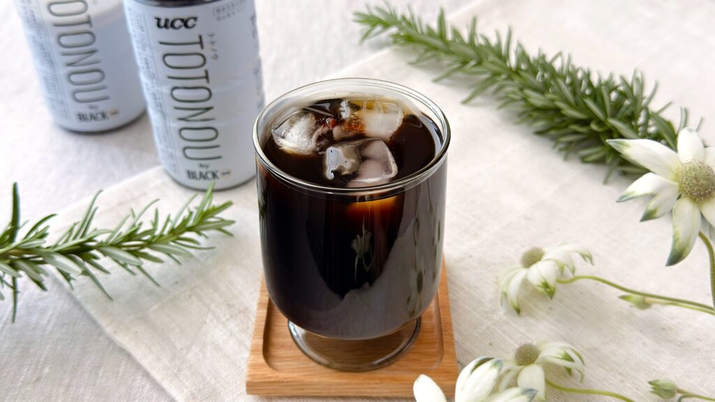 UCC_グラスにはいった「UCC TOTONOU(トトノウ) by BLACK無糖 PET500ml」とパッケージが並んでいる様子