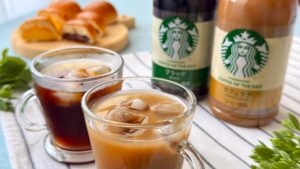 スターバックス_グラスに注いだ「スターバックス® コーヒー オブ ザ デイ ブラックと「スターバックス® コーヒー オブ ザ デイ カフェラテ」、パンの皿盛り