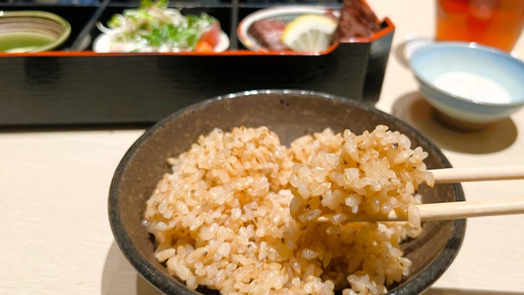ファンケル_創作料理 FANCL 令和本膳「美腸活弁当」の玄米ご飯を箸で持っている様子