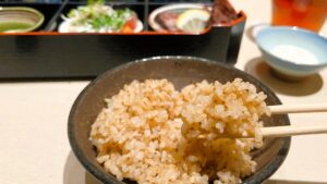 ファンケル_創作料理 FANCL 令和本膳「美腸活弁当」の玄米ご飯を箸で持っている様子