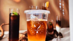 UCC_バリスタのいないアイスコーヒー専門店「ひみつのドリップ」の「コーヒーレモンスカッシュ（マイルド）」を持っている様子