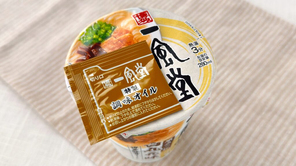 渡辺製麺_「博多豚骨ラーメン 一風堂白丸元味」の蓋についた特製調味オイルを取っている様子