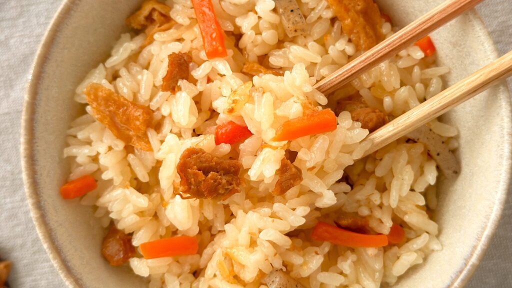 丸美屋_「柚子香る炊き込みごはんの素」で炊いたご飯を箸で持っている様子