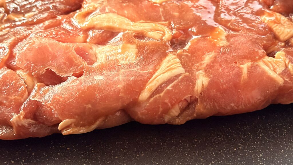 理研ビタミン_冷凍した「パッとジュッと® 旨だれ絡む豚生姜焼き用」をフライパンにのせている様子