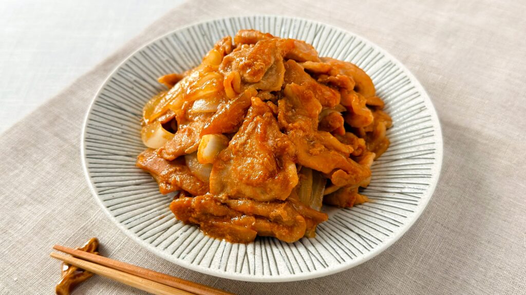 理研ビタミン_「パッとジュッと® 旨だれ絡む豚生姜焼き用」で作った生姜焼きの皿盛りと箸が並んでいる様子