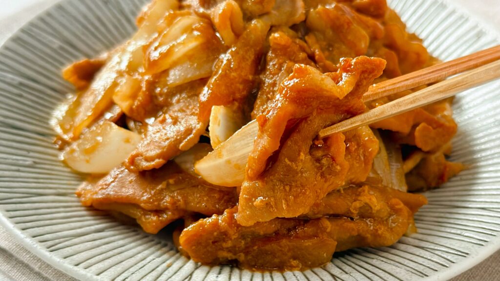 理研ビタミン_「パッとジュッと® 旨だれ絡む豚生姜焼き用」で作った生姜焼きを箸で持っている様子