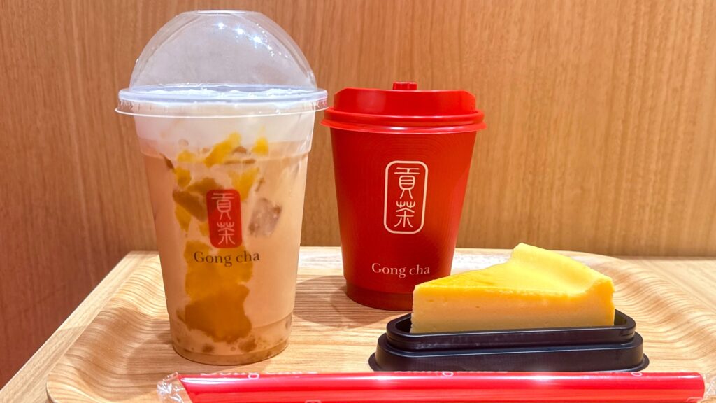 ゴンチャ_お盆にのった「紅はるか ミルクティー」のアイスとホット、ニューヨークチーズケーキがテーブルに並んでいる様子