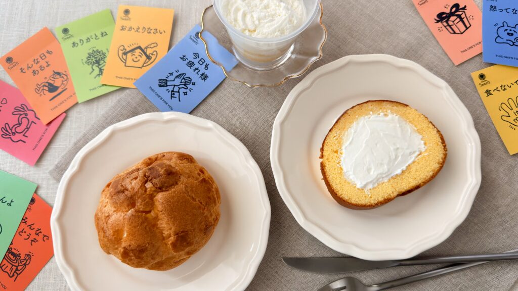 ファミリーマート_展示された「クリームたっぷり！ダブルシュー」や「生クリームロールケーキ」、「ほぼクリームのケーキ」の皿盛りとメッセージカード